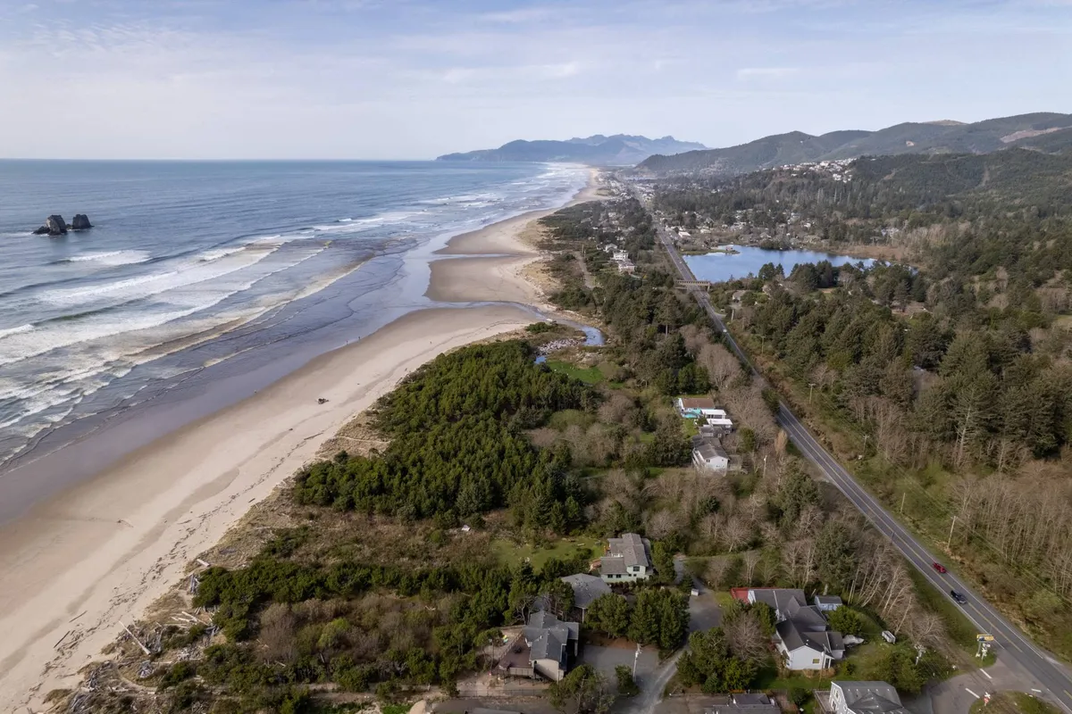 An expansive view of the coastline, showcasing rolling ocean waves, a sandy beach, coastal houses, and mountains in the distance. The scene is serene and inviting, evoking the sense of peaceful exploration and beachfront strolls described in the section.