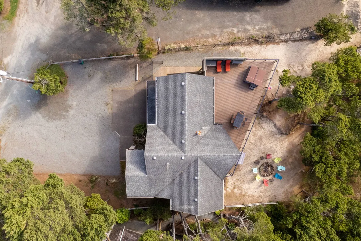 A tranquil exterior view with a modern deck area, comfortable seating, and a cozy fire pit, all surrounded by greenery. The setup is perfect for enjoying sunset views, socializing outdoors, and relaxing after a day of exploration.